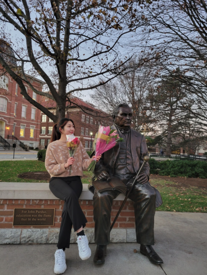 Cynthia hands flowers to John Purdue, the original benefactor of Purdue University. Courtesy of Cynthia Choi.