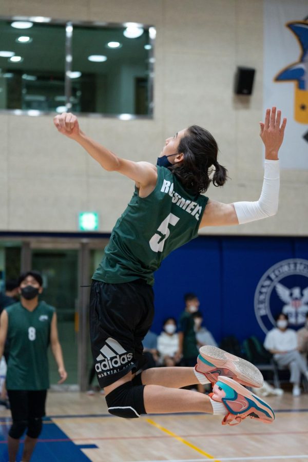 Ethan soars above the net to spike the ball. Photo by Lewis Kim.