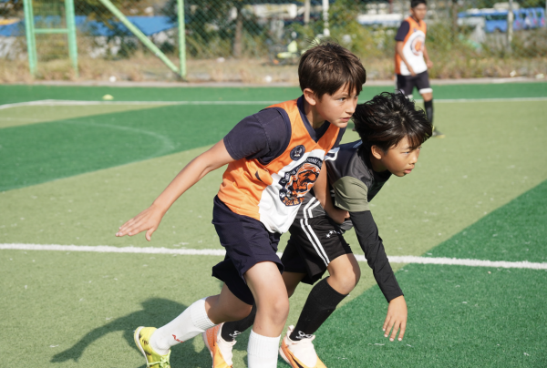Midfielder Gio Park competes against a GIFS defender for a possession. Other teammates wait for the pass. 