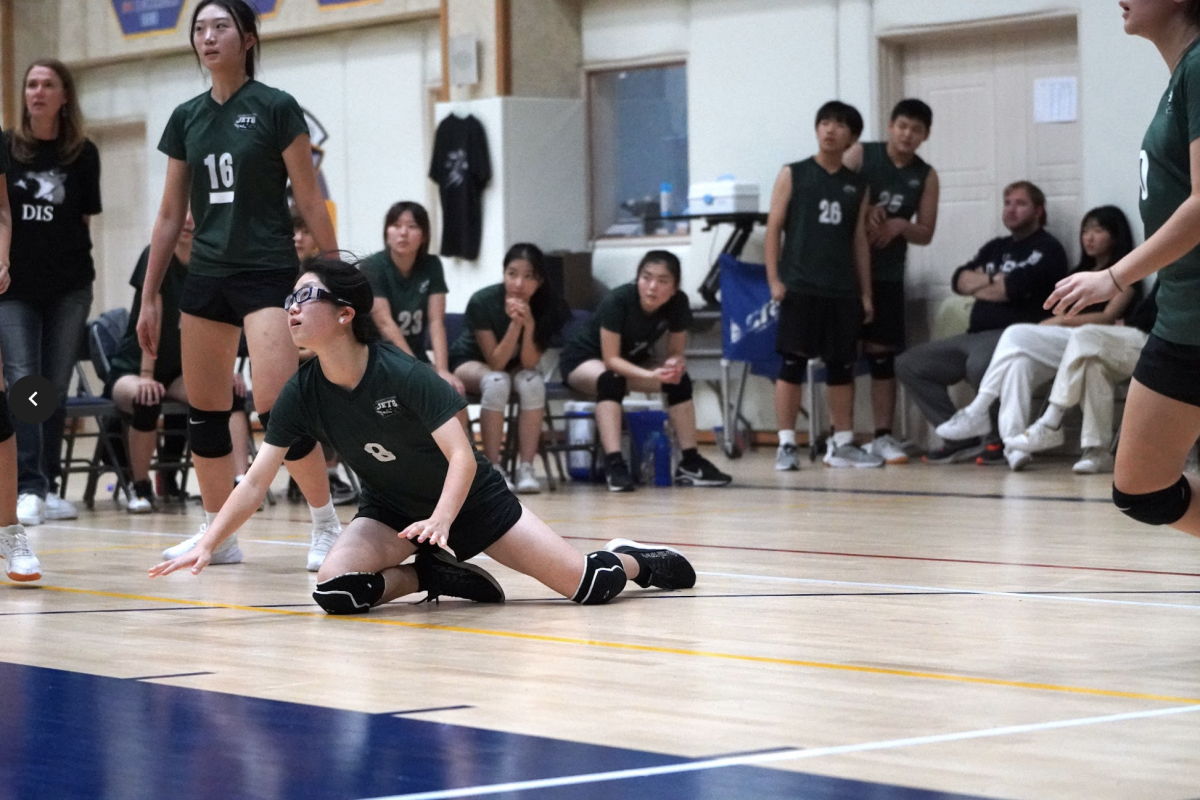 Minori Kojima, co-captain, dives onto the floor to save the ball from touching the ground. Minori quickly realizes the trajectory to get there on time. The crowd roars after the super save. 