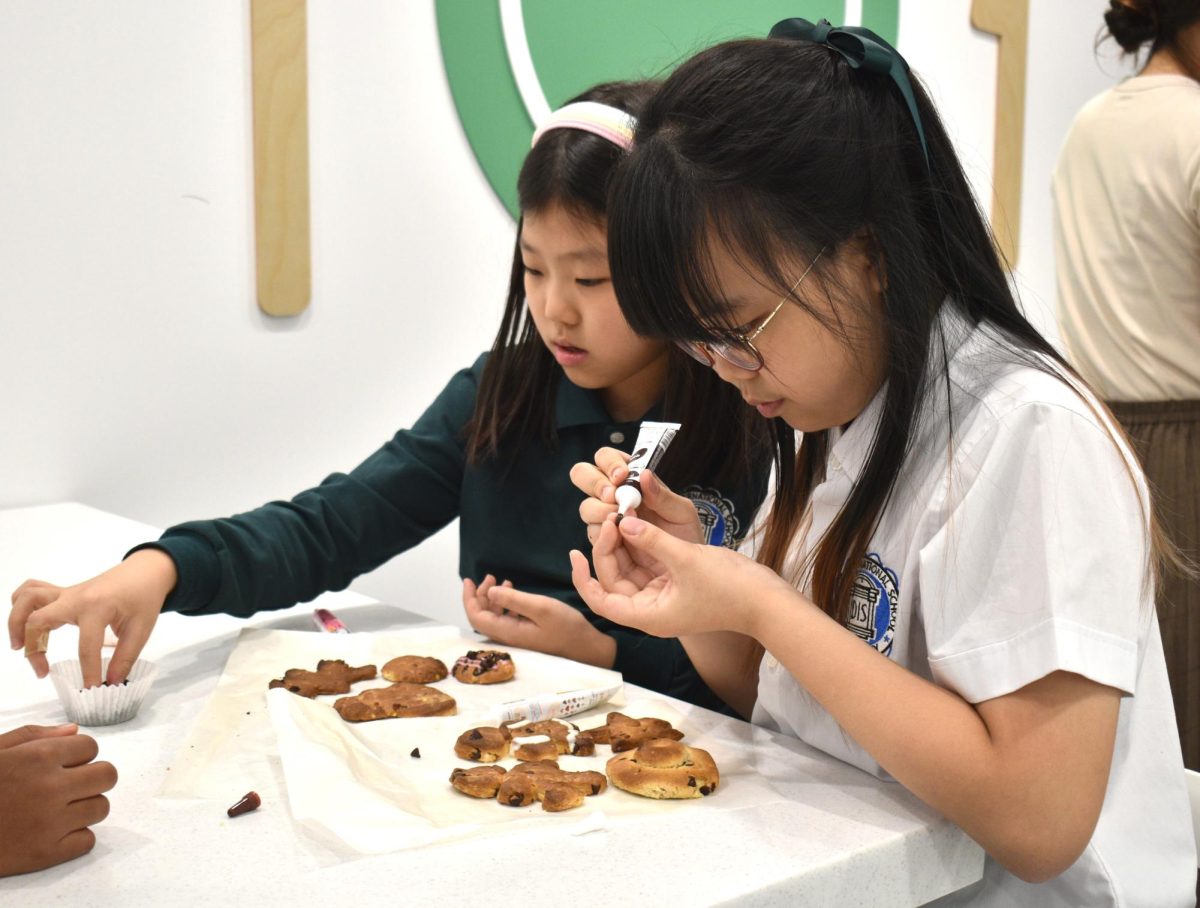 Intently engaged in her artwork, second-grader Viviana Kwon prepares to sketch sweet animals onto her chocolate chip cookies. 