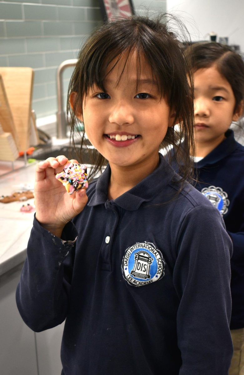 Soi Shin in 2nd grade presents her latest creation: a star-shaped cookie topped with a colorful array of sprinkles, chocolate, and strawberry syrup. 