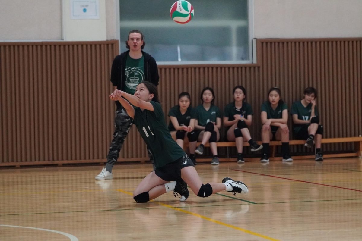 Sophomore Anna Yoon dives to save a tough spike from NLCS. Coach Balint gasps in awe at the hustle play. 