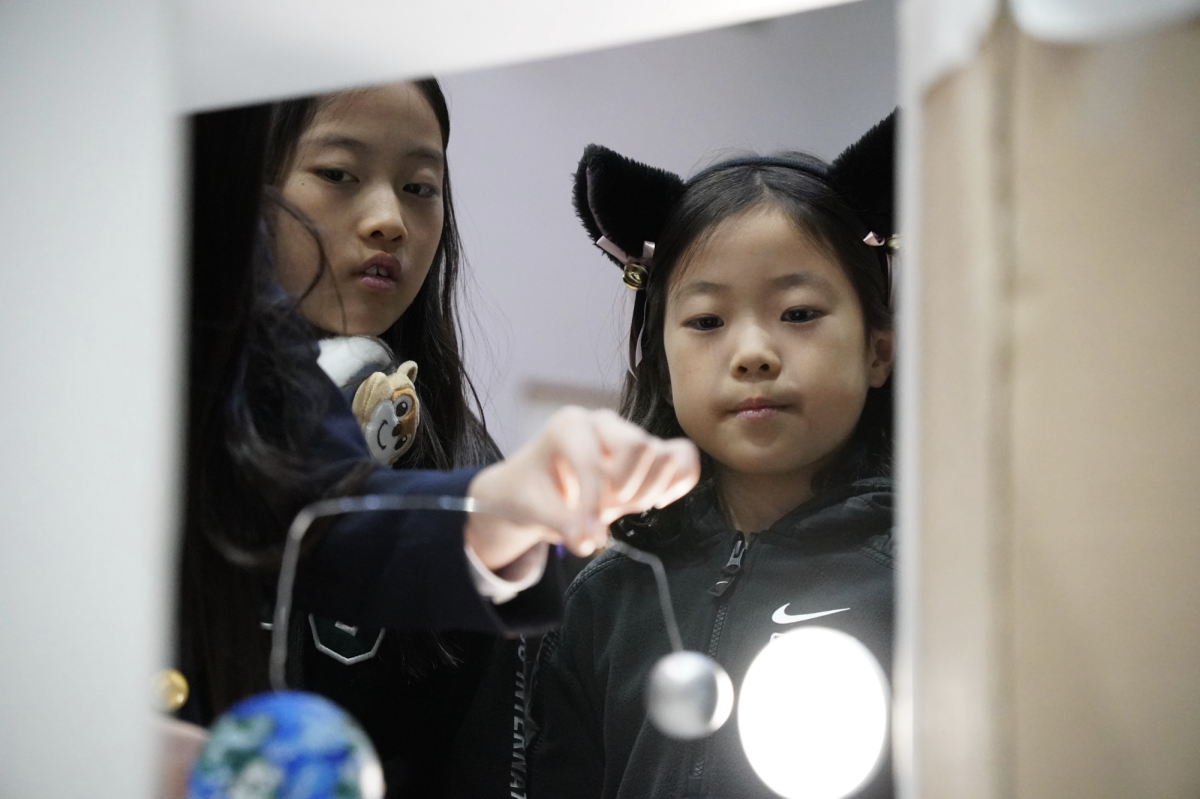 A cosmic-themed project grabs the eyes of third-graders Belle Kim and Raina Kang. They dive deeper into the mysteries of the universe. Photo by Jackson Chiang.