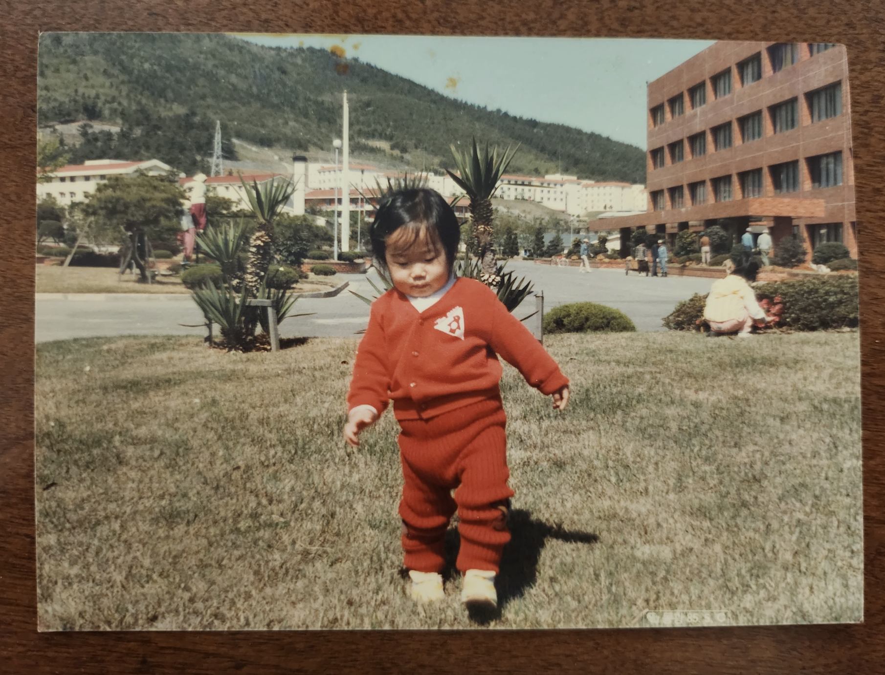 Mrs. Je brings back a childhood photo of the three-year-old herself in Geoje. She poses in front of her fathers workplace. Photo courtesy of Mrs. Je.