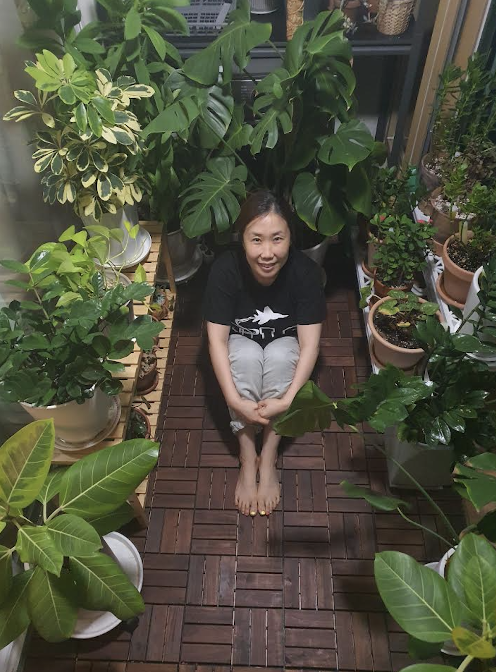 Mrs. Je enjoys a breath of fresh air from her green-children she raised with her green thumb. She grows many different types of flora in her balcony. Photo courtesy of Mrs. Je.