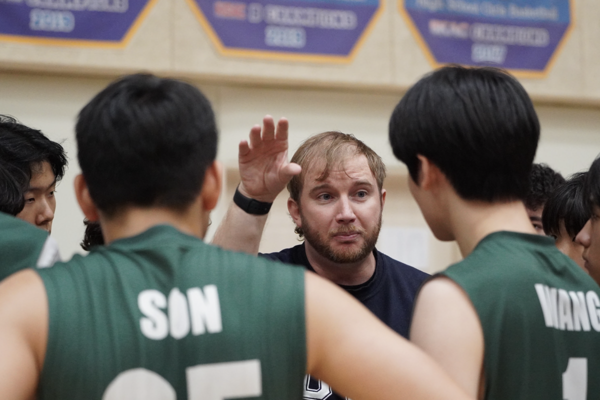 Coach Bergan discusses news strategies with his team in the HS Volleyball Busan Invitational on October 28th. The air is tense as the two schools plan for their next game. Photo by Flora Chung.