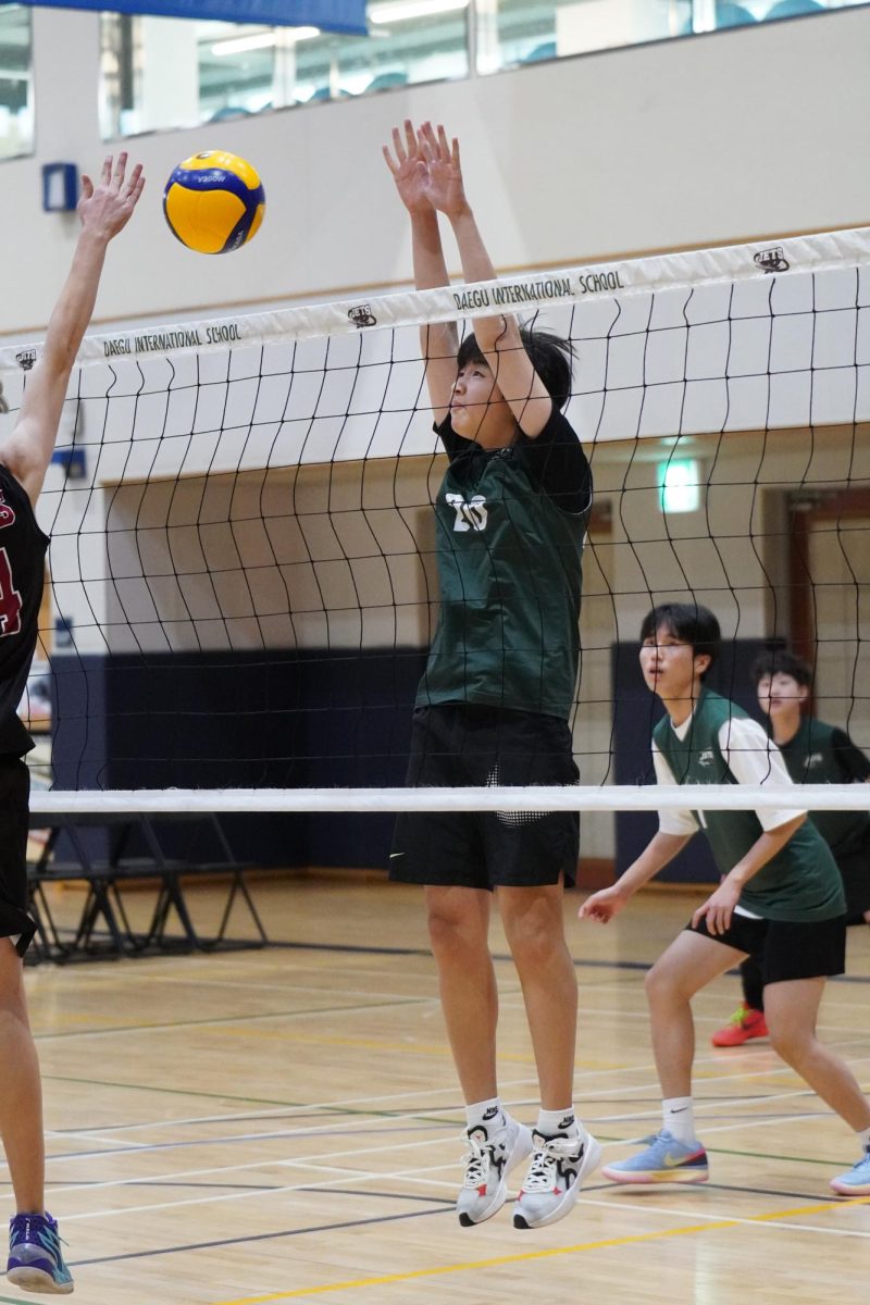 Matthew Park (number 20) springs up for the block against the opponents tip. His teammates are ready to dig up the ball, which gives Matthew the confidence to focus on the block. 