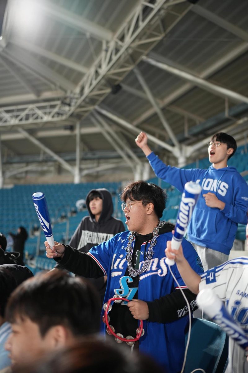 Avid Lions fans junior Tommy Jang and senior Bolt Yi shake their merch and sport their uniforms in support of the team until the very last. Their fervor sparks hope in the Lions.