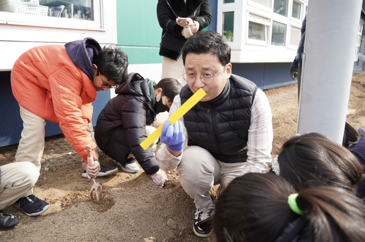 Mr. Bae instructs fourth graders about the specific depth that the potatoes have to be planted in. This process ensures the robust foundation of the sapling. 