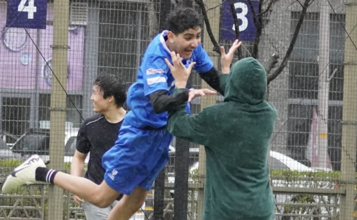 Sophomore Ali Karam jumps for joy as junior Harrison Sung celebrates Alis monster goal. The boys soak up the rain but they seem happy to escape indoor play for the last few minutes of practice. 