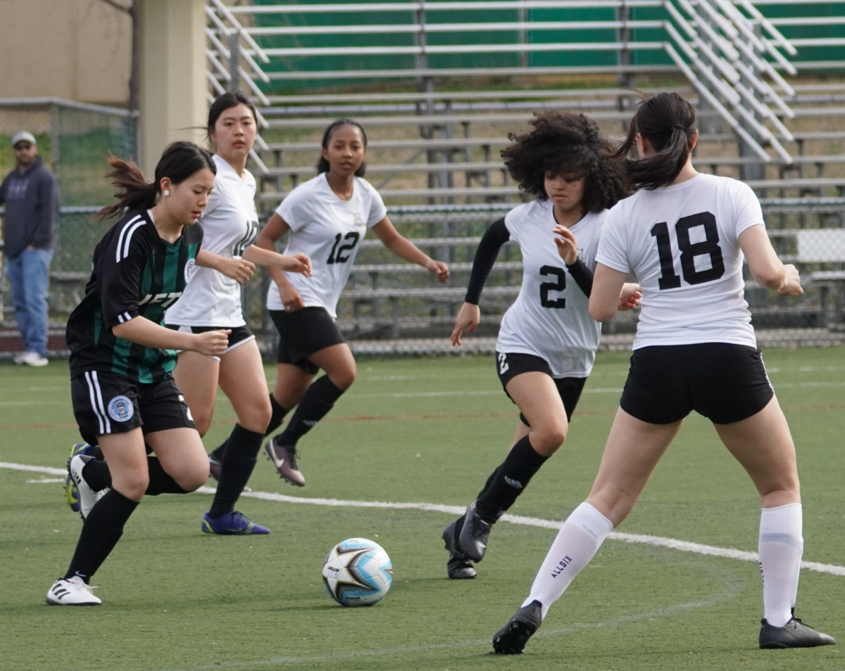 Midfielder Leewen Wang dribbles across the field and gets through five defenders. Her teammate Amy sprints to assist her. 
