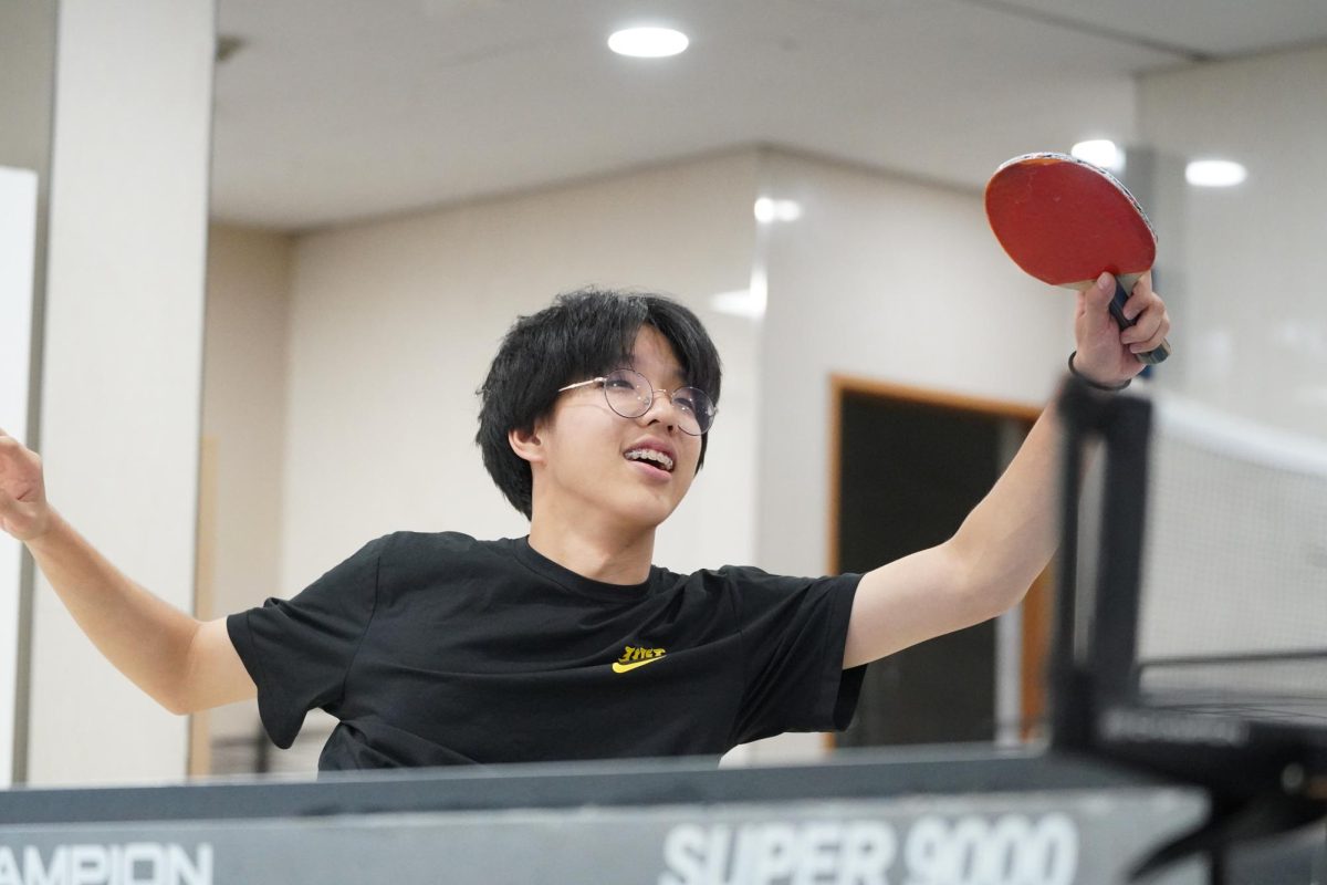 Brian Cho in 11th grade stretches his arms to reach the ping-pong ball with his injured legs. He aims to win the bet against fellow junior, Brian Hyun. 