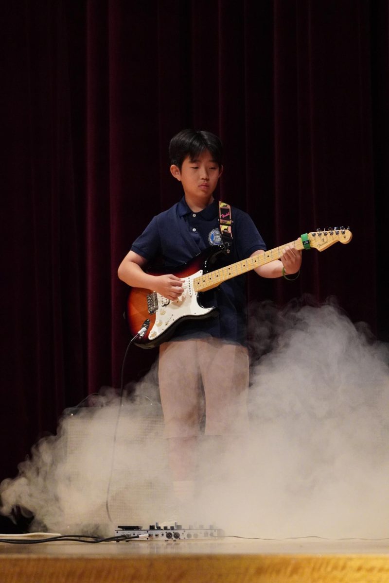 Brian Kim in fifth grade strums his guitar with each note forming a harmony with the whole band.