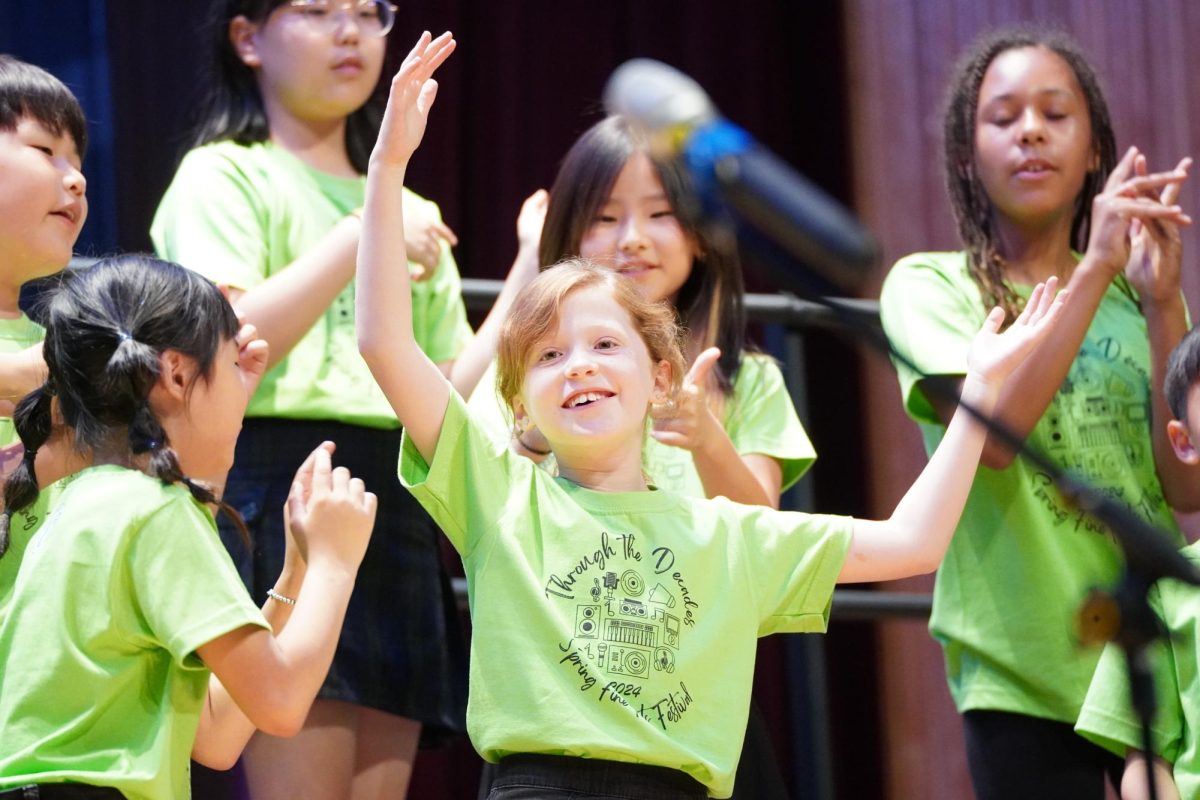 Louise Marechal throws her hands up in the air, elated by the performance. Her peers cheer her on. 