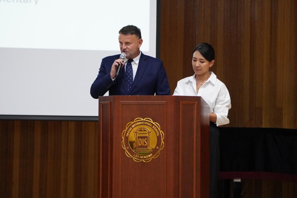 Mr. Jolly greets all parents and thanks them for coming. Next to him stands Ms. Katie Kim, who translates Jolly's presentation.