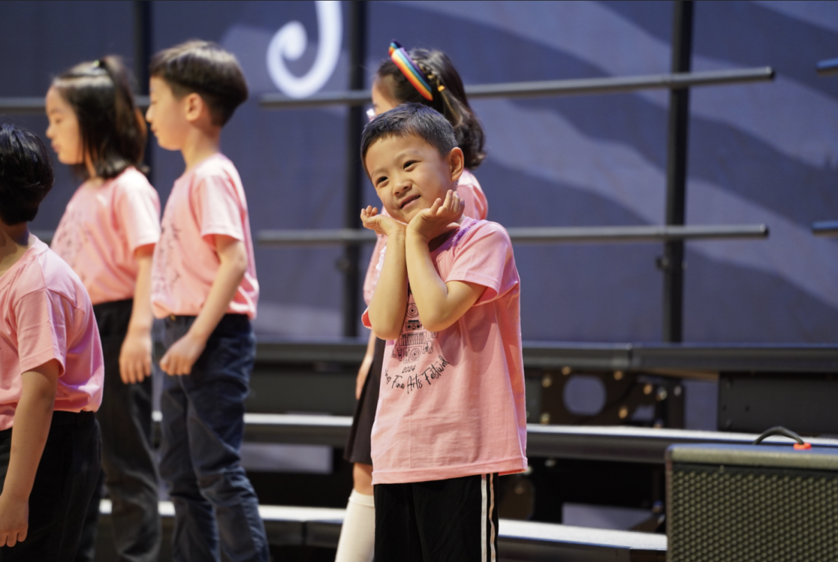 Yize Li in kindergarten takes some time to calm down his nerves as he waves to his parents before the final number of the concert. 