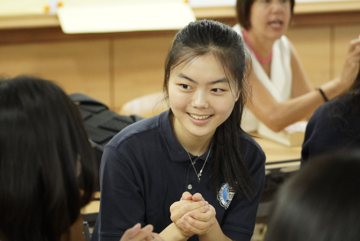 Junior Apple Jun excitingly rolls the dice as she waits for her turn in the back-to-school game in her Spanish class. 