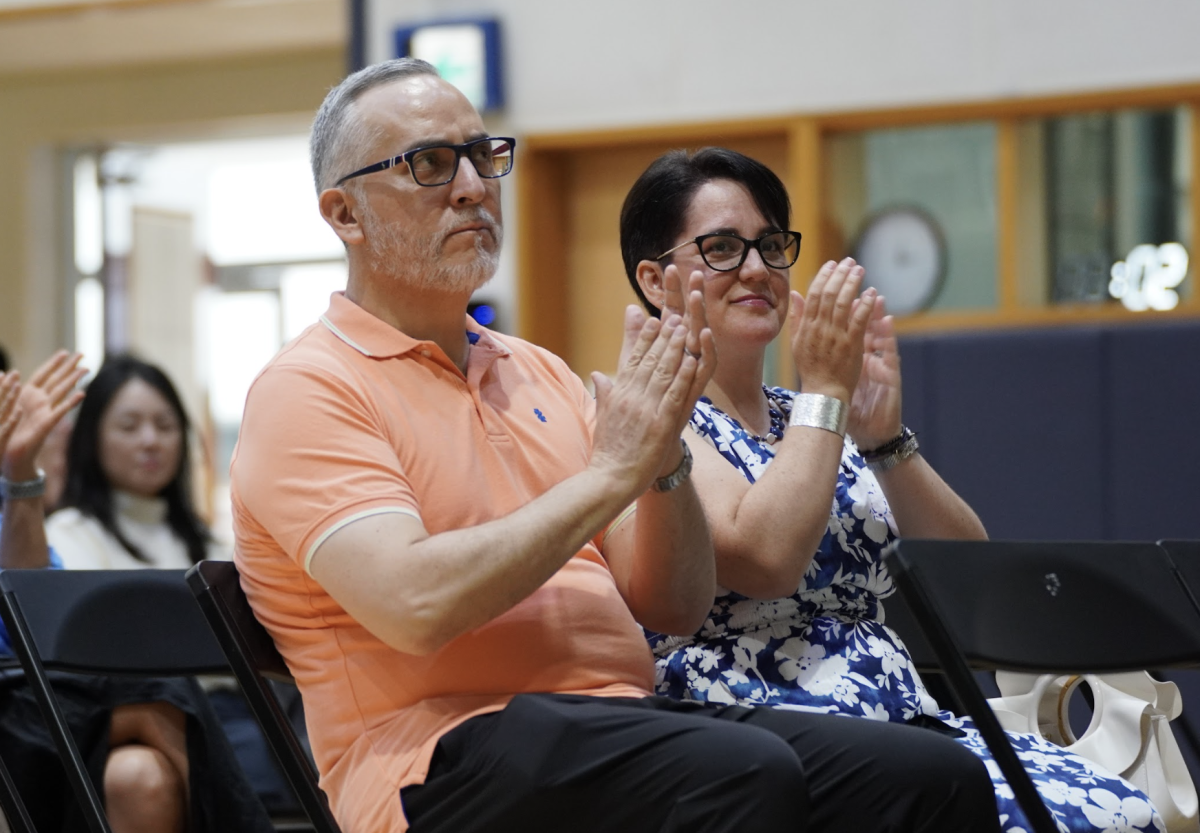 The audience erupts into applause as head of school Mr. Jolly heads up to the stage. Jolly is about to announce the different changes implemented to DIS as well as upcoming events.