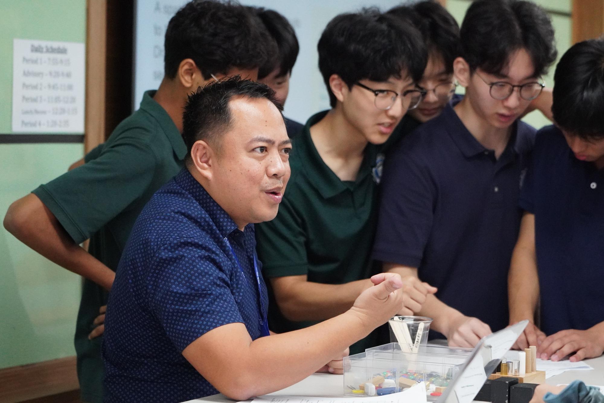 Surrounded by attentive students, Mr. Hortezuela passionately unravels a complex problem, his eyes light with enthusiasm as he explains every detail.