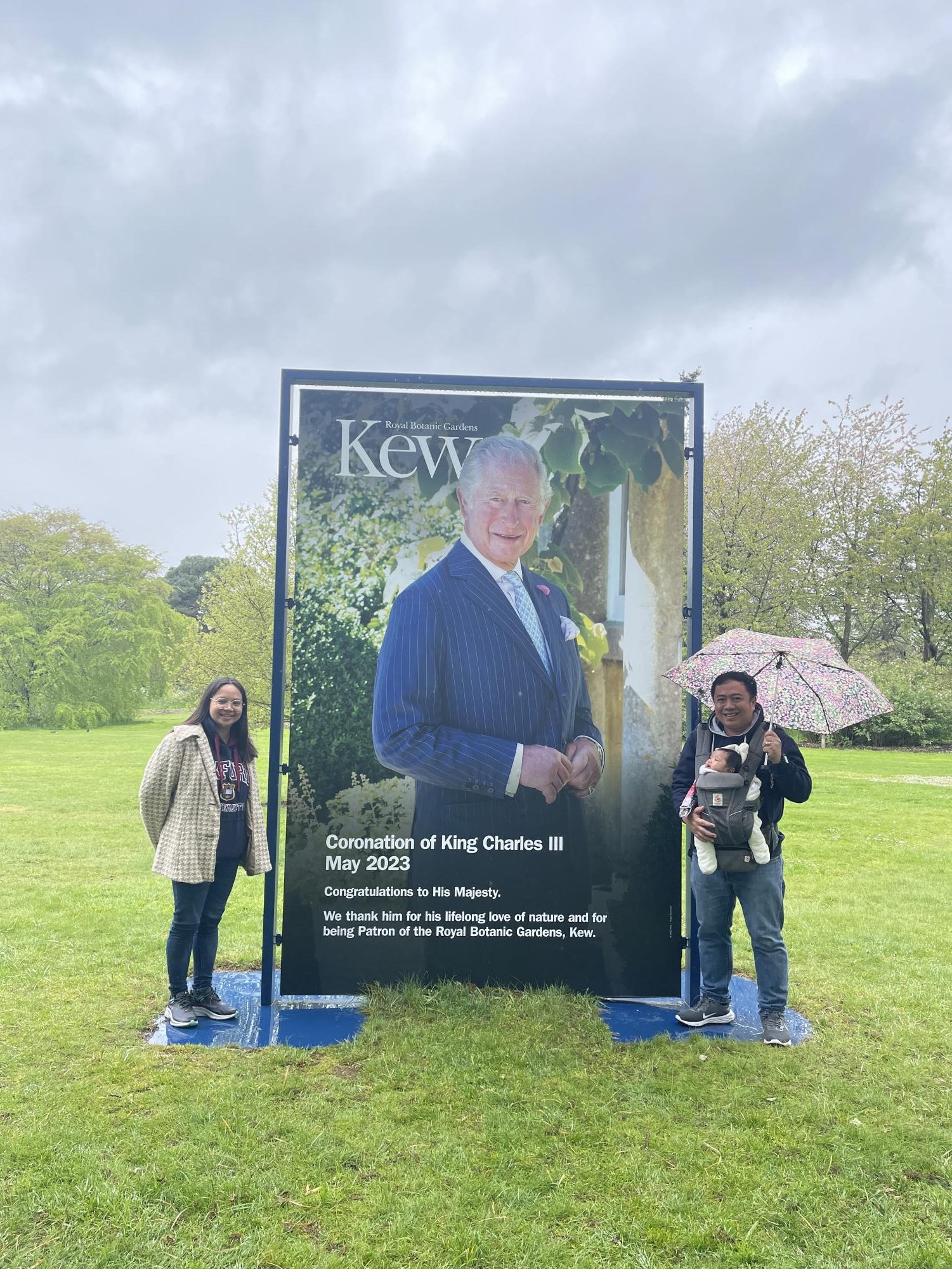 Mr. Hortezuela and his wife AC Griffith stand proudly beside King Charles III's vibrant coronation poster at Kew Gardens. Photo courtesy of Mr. Hortezuela. 