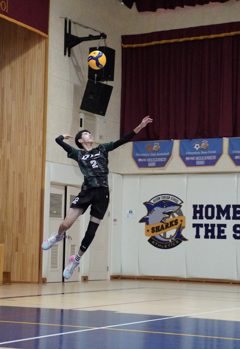 Outside hitter Evan Rossmeisl (number 10) soars for a jump float serve. He aims it to the weak defensive areas.