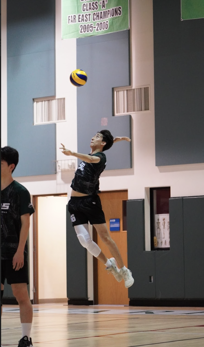 Haydn Mangione soars for the floater. It travels unpredictably as the opponents shanks it. The crowd shouts "ace" and uplifts the varsity squad. 