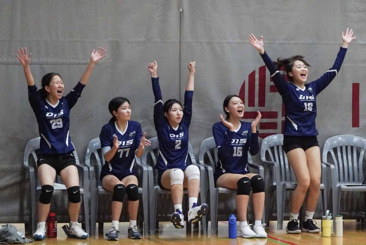 The varsity girls celebrate after a serve ace by Victoria Kang. They cheer on their teammate and hope she maintains the momentum. 