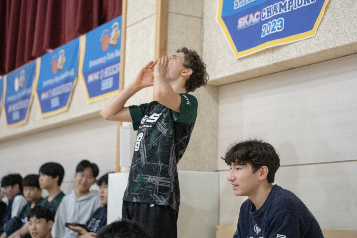 JV1 setter Maddox Jolly (number 8) shouts "Jets Fighting" during the varsity finals. His loud roar echoes within the gym, boosting the players' performance and school spirit at the home of the Sharks. 