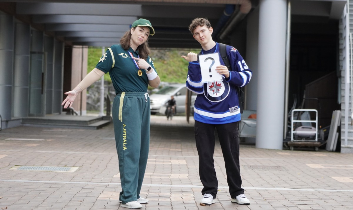 Mrs. Gum and sophomore Maddox Jolly bring a playful twist to Sports Day, with Mrs. Gum dressed in tribute to Australian breakdancer Rachael Gunn and Jolly adding mystery by holding up a question mark. Their lighthearted poses add a sense of fun and curiosity to the event. 