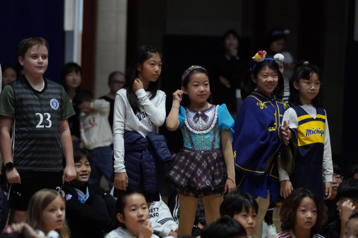 The elementary school soccer players stand proudly as their friends applaud them for a successful futsal season. Their sports uniforms fit perfectly with the occasion. 