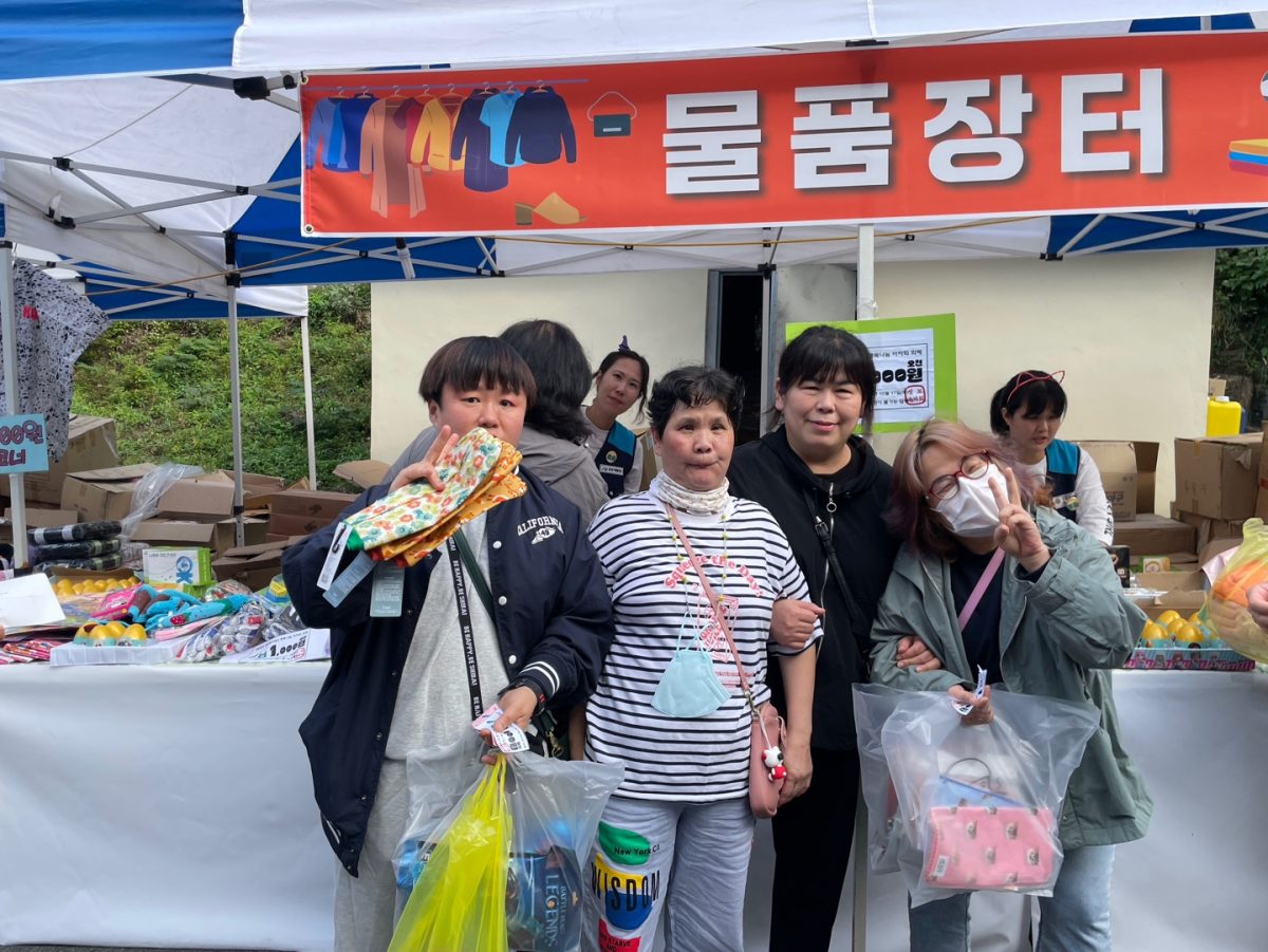 Residents of faith hall gather together for a picture to capture the exciting moment, their hands full with all the goods they bought. 