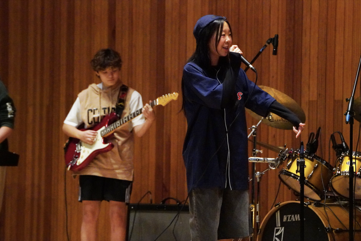 Sophomore Sophie Lee vibes to the lyrics of "Some." She makes eye contact with fellow vocalist Aiden Huh as they stack harmonies. In the background, sophomore Jayden Hayward supports Lee's vocals on the electric guitar.