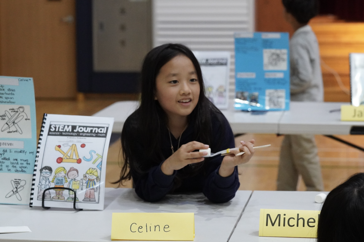 Celine Park, a third-grader, carefully adjusts her catapult before launching a test shot. Her determination shines as she watches the projectile soar through the air. 