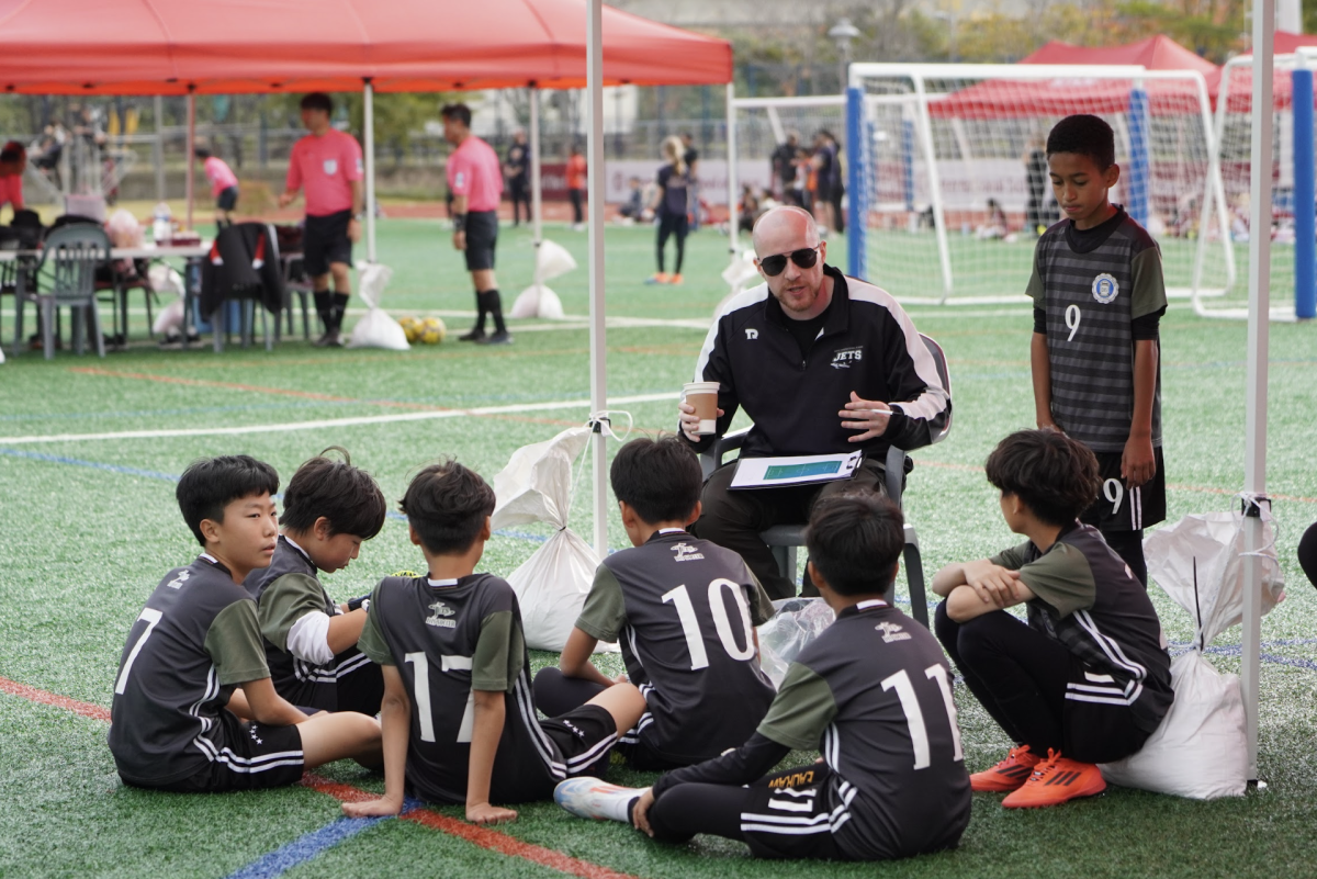 Mr. Purdy rounds up the boys' A team for a quick debrief of their most recent game. He praises the players and offers a couple pointers. 