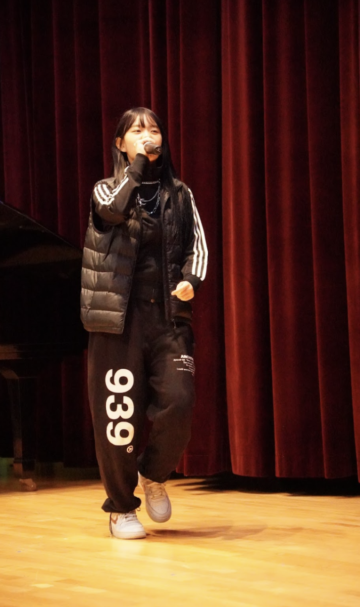 Senior Hailey Tzou steps onto the stage from behind the curtain to deliver her energetic verse of the rap song “We Higher.” She captivates the crowd with her steady tone despite the fast-paced beat. 