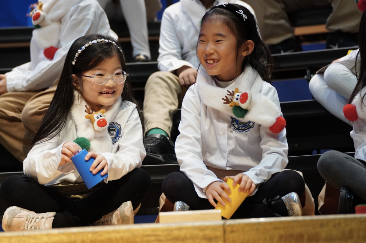 Second-graders Aileen Kim and Juwon Kim hit all the right notes as they make music come alive, clapping, tapping, and smiling as they share the excitement of the winter festival. 