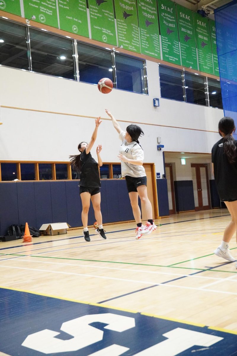 Sophomore Ellen Cho pops a jumper above the outreached arms of the defenders. She locks aim at the rim and lets the ball fly. 