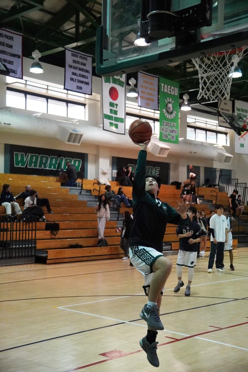 Junior Ryan Chae runs through his warm up regimen before the game kicks off. Though nervous, he prepares to join his first game on the varsity squad at any moment, adapting to the DMHS court by practicing a layup.
