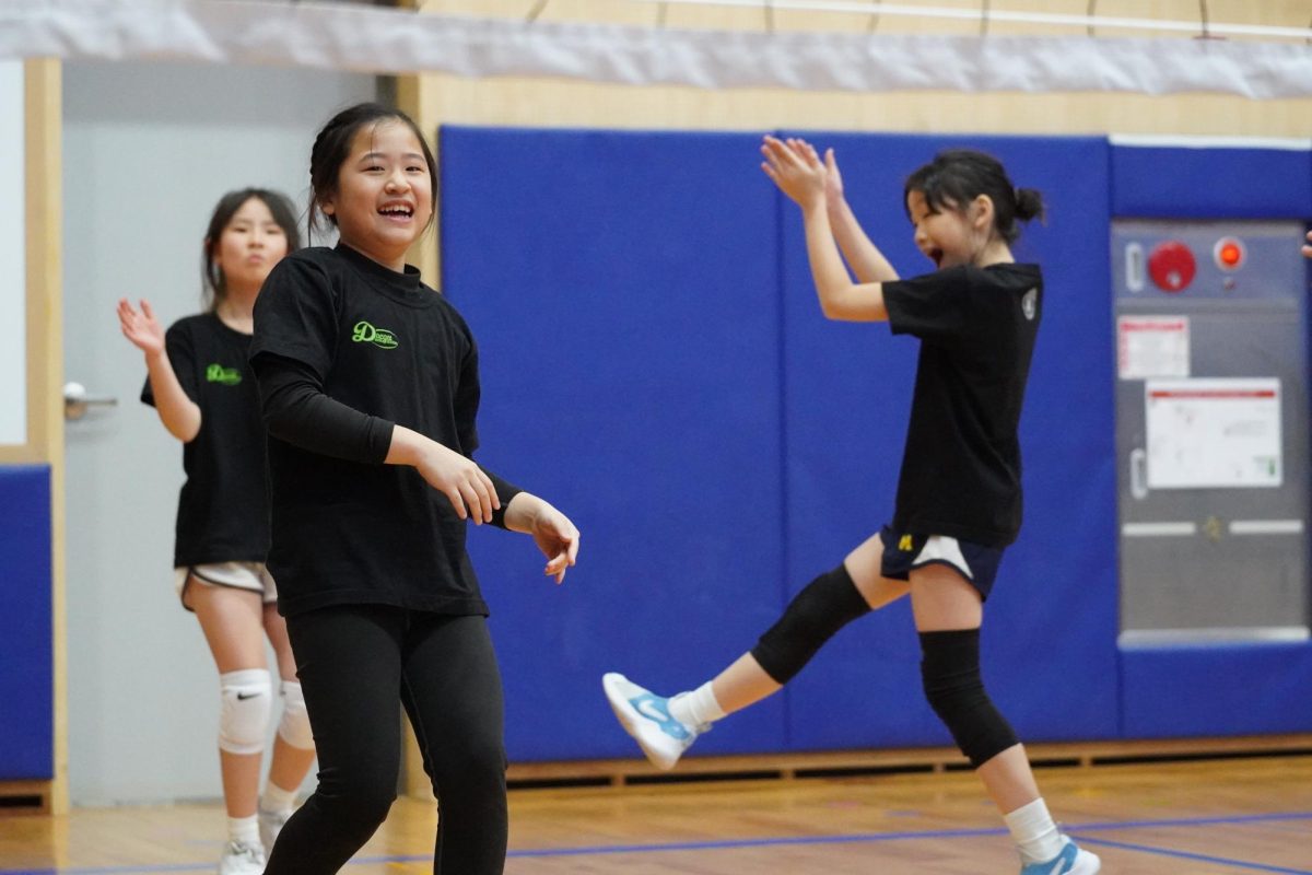 Fourth graders Jenny Lee, Amelia Kim, and Amelia Park celebrate their hard-earned point with a team. They eagerly prepare for the next rally against their opponents. 