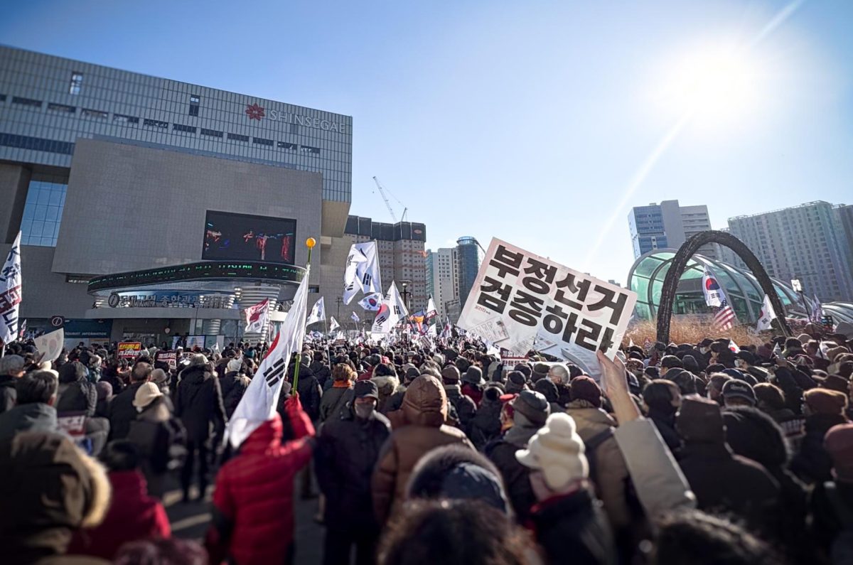 A protester raises a sign demanding an election audit as thousands of others chant in support of President Yoon. 