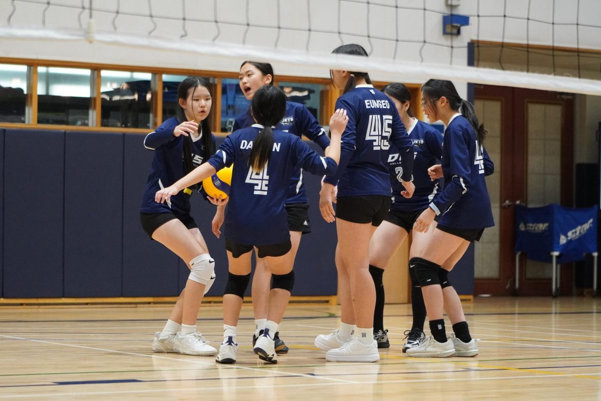 The DIS 3 team huddles in for a team cheer after a victorious point. Captain Olivia Park (number 5) leads the rally with her prominent voice and leadership.