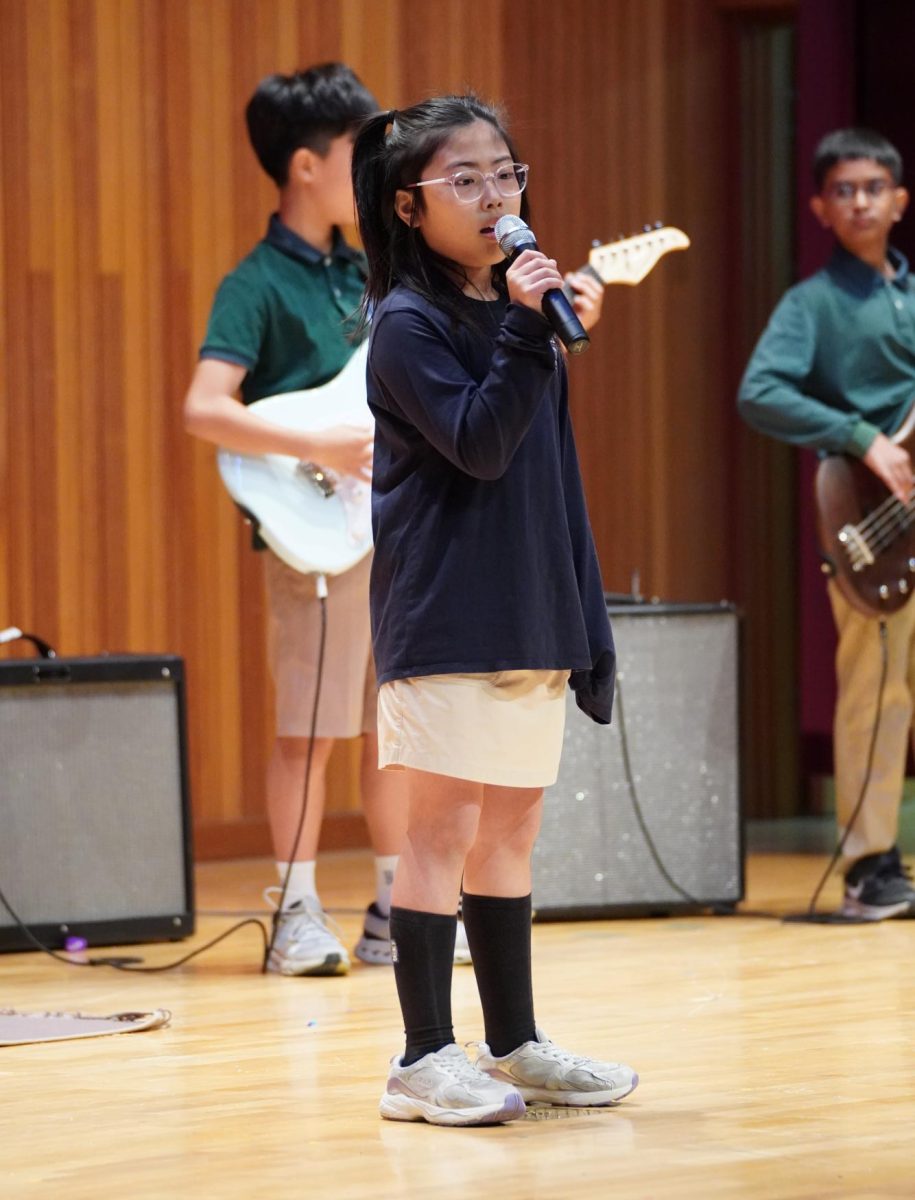 Third-grader Ruby Kim sings in harmony with her fellow vocalist ___. Their rendition of ____ by ____ closes the assembly with a bang.