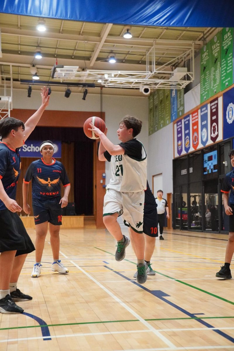 Sixth grade varsity starter Aiden Hwang (number 21) sprints under the paint and scans around for a lob pass towards his teammate. His chance-making opportunities lead the team to score easy buckets. 
