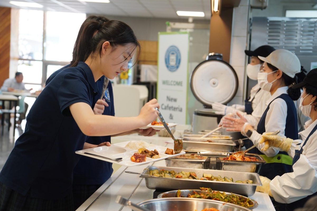 Freshman Stella Kwon serves herself a portion of savory acorn jelly salad. With the new staff in place, the cuisine brings a refreshed flavor compared to last year.