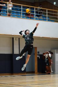 Outside hitter Evan Rossmeisl (2) leaps forward to unleash a powerful float jump serve. His precision allows the ball to drop right in front of the opponents’ defensive positions. 