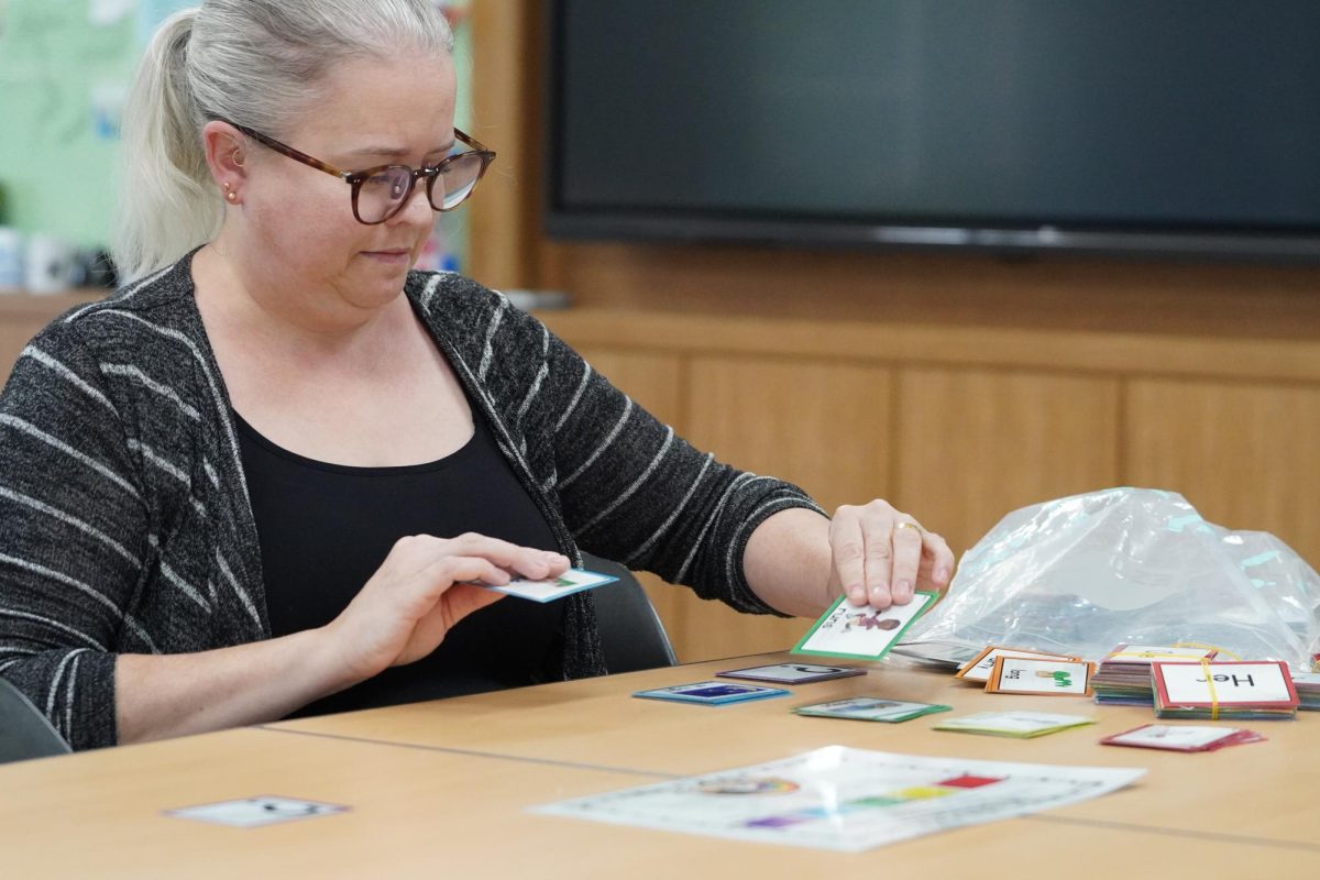 Mrs. Willette diligently lays out vocabulary cards on her deck. The colorful rims of the cards reflect her playful and quirky personality. 