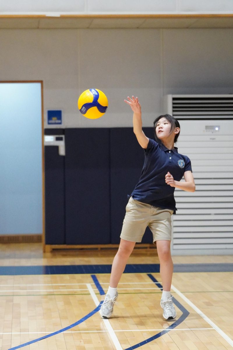 With one mighty fling, Sixth-grader Evelyn Cho spikes the ball. As the volleyball meets its target, a satisfying “smack” fills the gym. Photo by Esther Choi. 