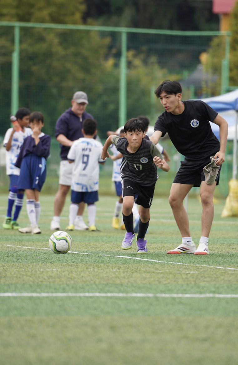 Student Coach Robert Cho directs Weejee Kung in fifth grade toward the ball near the sideline. His professional tactics strengthen the team's offense and defense. 