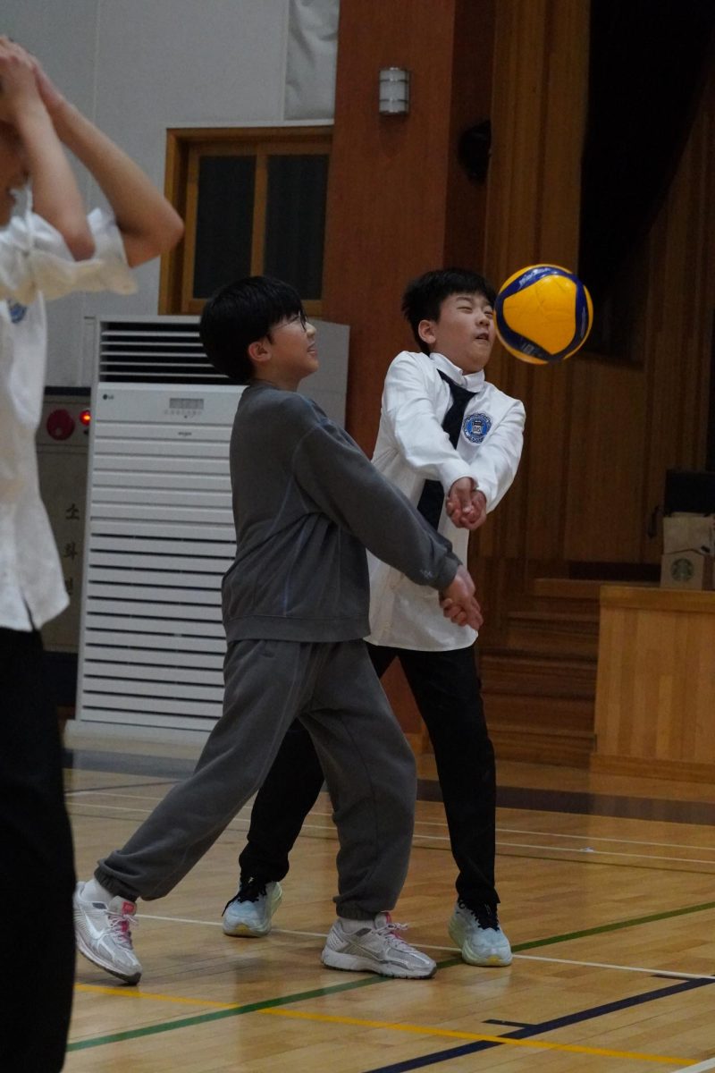 Sixth graders Robert Koo and Joshua Kim rush for the ball, determined to keep the play alive. With a dramatic bang, they successfully bump it up in the air.